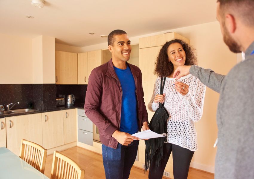 person-handing-key-to-couple-in-kitchen