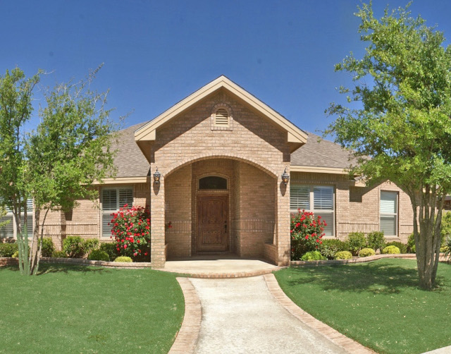 Exterior of a stone home in Heritage Oaks with trees and a green lawn